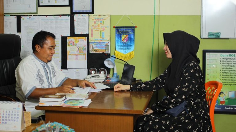 ولي أمر يجتمع مع مسؤول مدرسة لمراجعة أوراق تعليمية