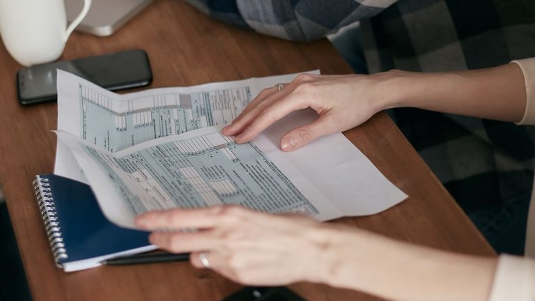 مراجعة مستندات ضريبية على مكتب مع آلة حاسبة وحاسوب